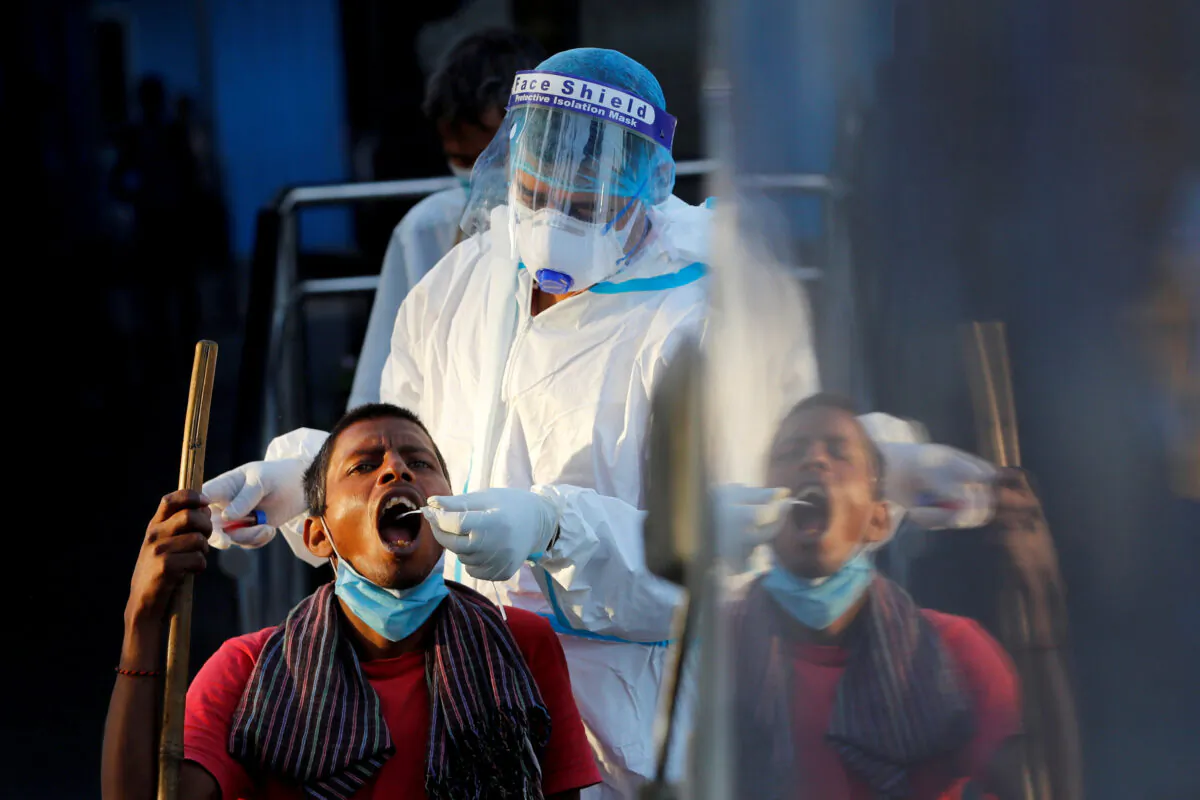 A healthcare worker collects a CCP virus test swab sample from a man, at a temporary shelter for homeless people in New Delhi, India, on March 31, 2021. (Adnan Abidi/Reuters)