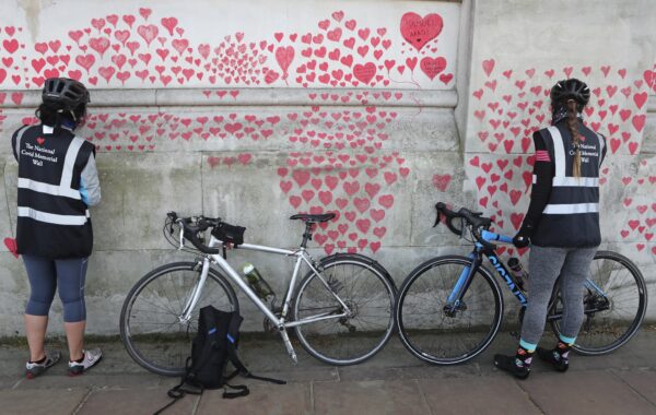 Women draw hearts on the 'The National COVID Memorial Wall'