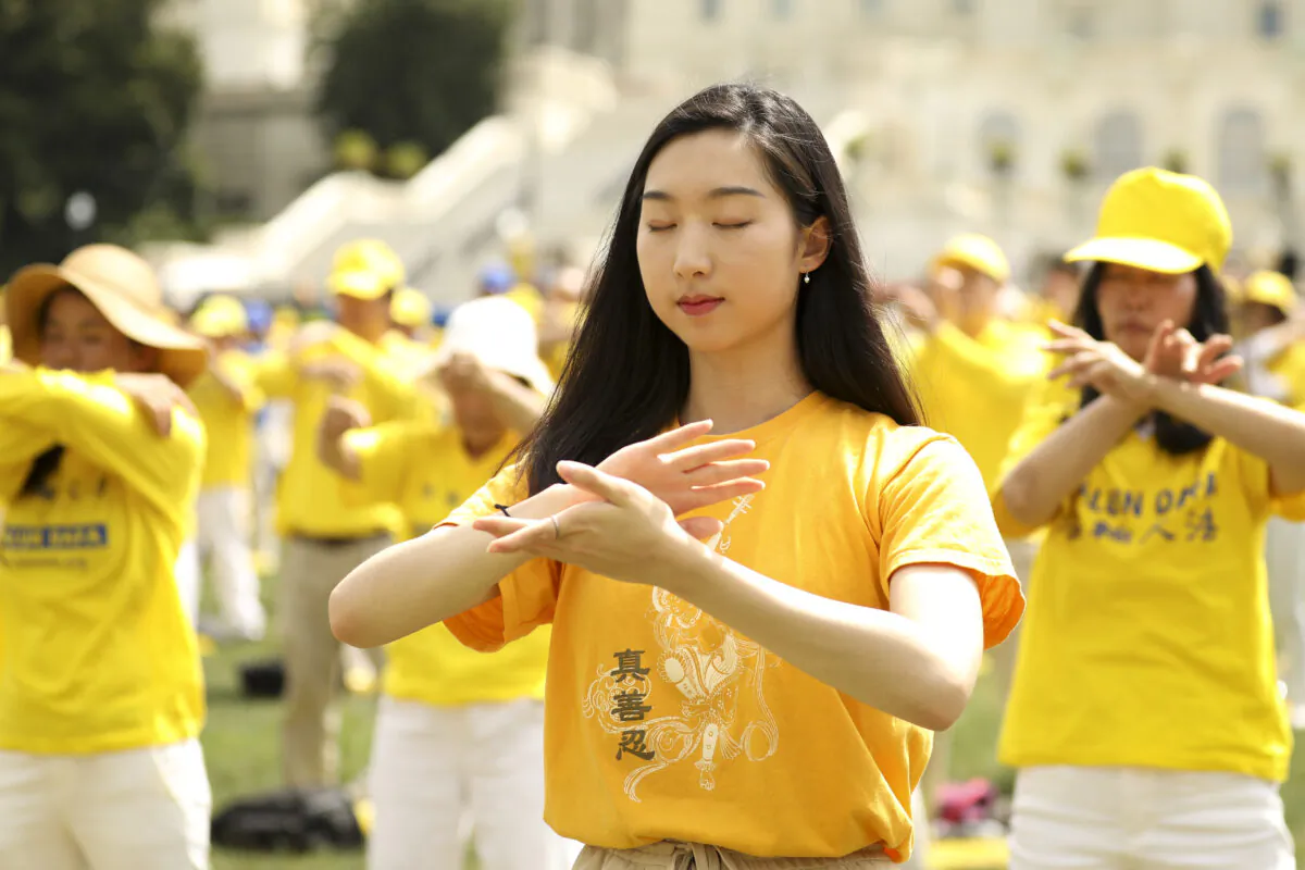 Falun Gong practitioners perform slow-moving exercises at a rally commemorating the 20th anniversary of the persecution of Falun Gong in China, on the West Lawn of Capitol Hill on July 18, 2019. (Samira Bouaou/The Epoch Times)