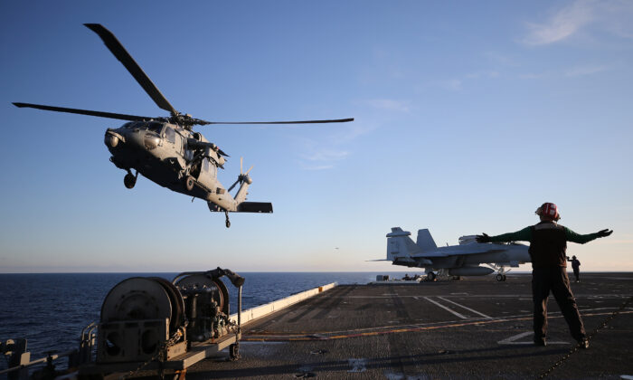 A U.S. Navy helicopter descends to land on the flight deck of the USS Nimitz (CVN 68) aircraft carrier while at sea off the coast of Baja California, Mexico, on Jan. 18, 2020. (Mario Tama/Getty Images)