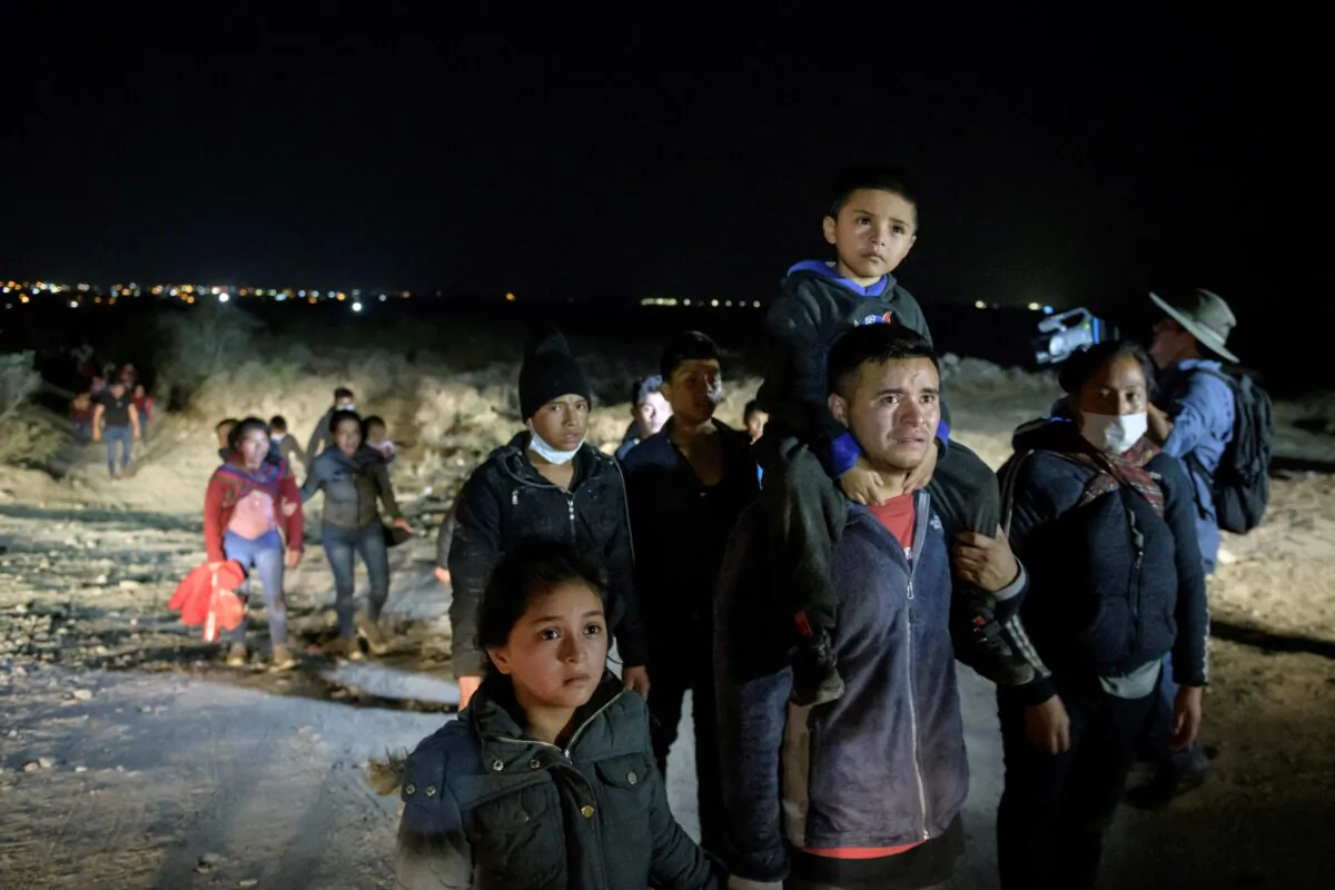 Immigrants who arrived illegally from across the Rio Grande river from Mexico make their way along a track towards a processing checkpoint set up by Border Patrol agents in the border city of Roma, Texas, on March 27, 2021. (Ed Jones/AFP via Getty Images)