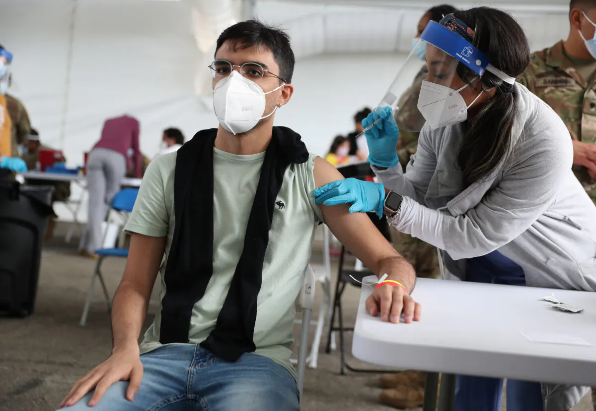A health care worker immunizes Juan Guevara with the Pfizer COVID-19 vaccine at the Miami Dade College North Campus in North Miami on March 10, 2021. (Joe Raedle/Getty Images)