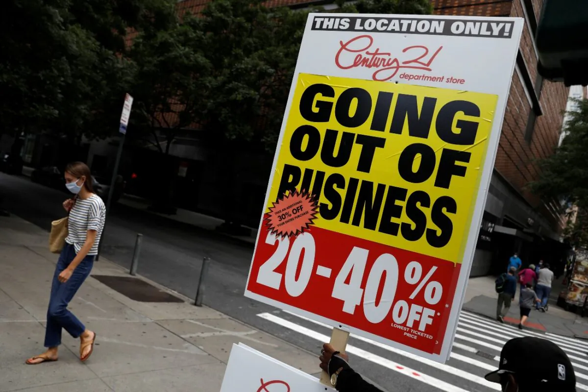 A person holds a sign advertising a sale at Century 21, a retail outlet that announced it was filing for bankruptcy and closing its stores due to the economic impact of COVID-19, in New York City, on Sept. 26, 2020. (Andrew Kelly/File/Reuters)