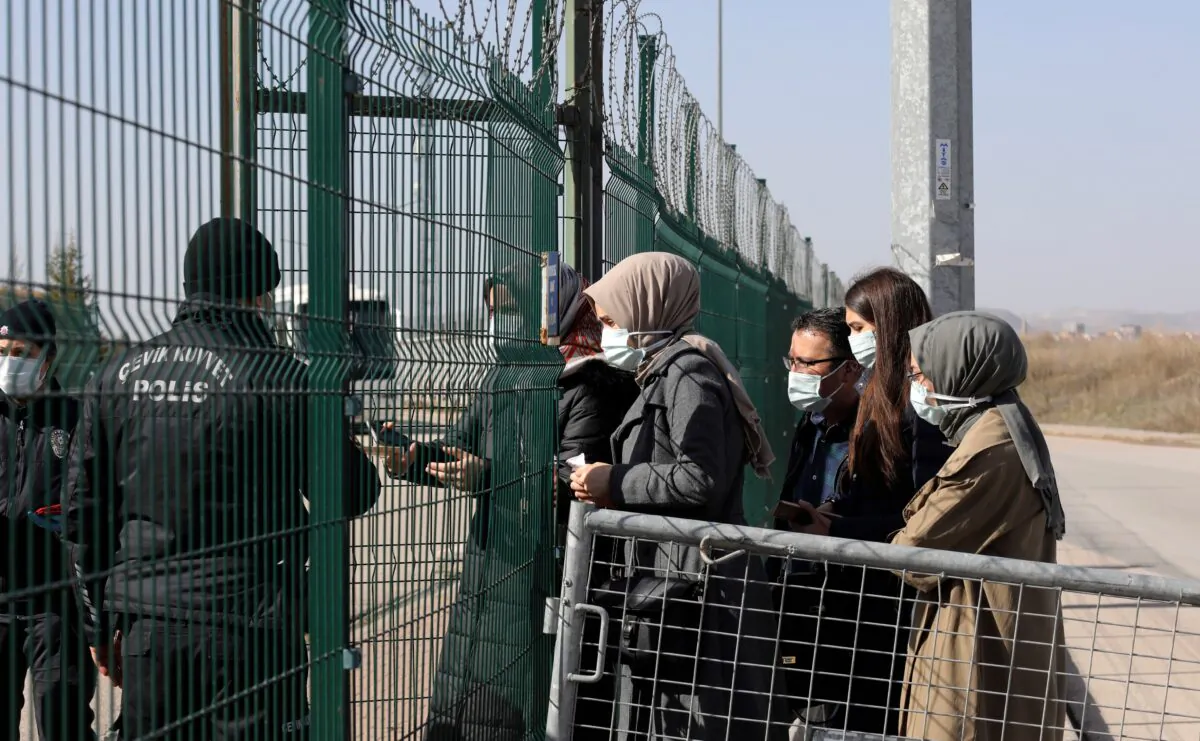 A police officer checks IDs as people enter a courthouse before the trial of 497 defendants, in Sincan, outside the capital Ankara, Turkey, on April 7, 2021. (Burhan Ozbilici/AP Photo)