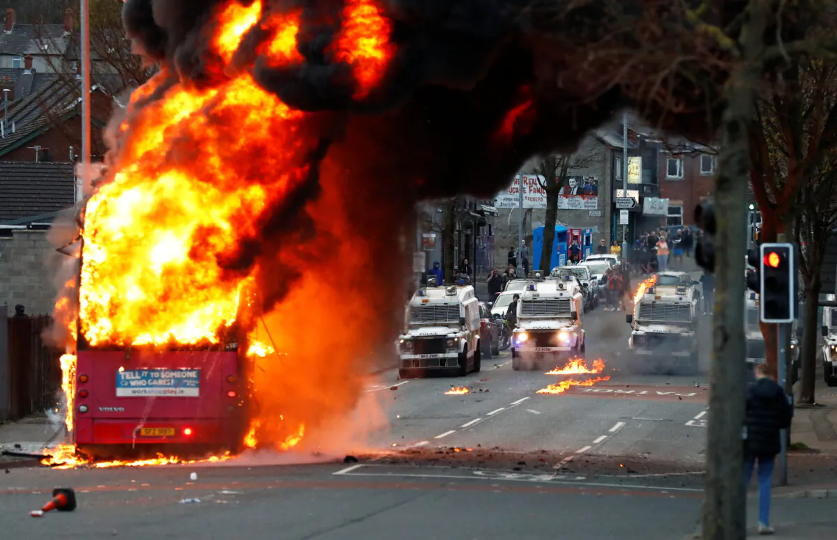 Police vehicles are seen as a hijacked bus burns on the Shankill Road as protests continue in Belfast, Northern Ireland, on April 7, 2021. (Jason Cairnduff/Reuters)