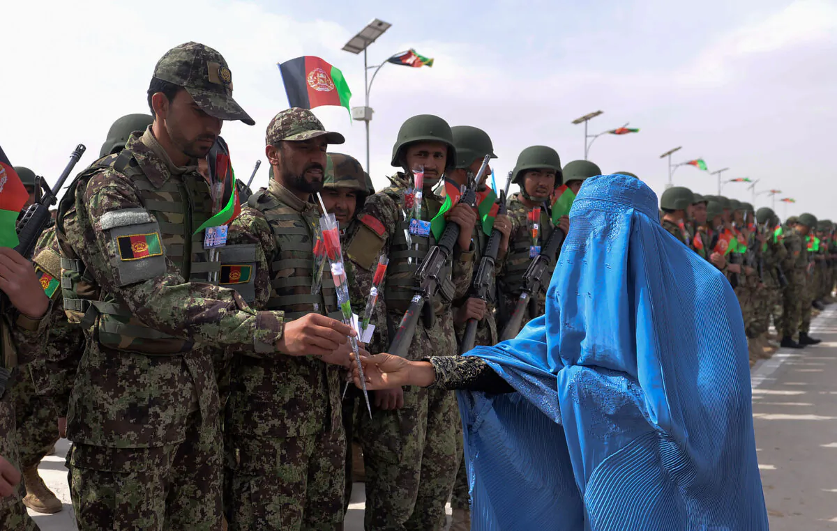 An Afghan woman wearing a burqa gives roses to Afghan National Army (ANA) soldiers during a ceremony in a military base in the Guzara district of Herat Province on Feb. 28, 2019. (Hoshang Hashimi/AFP via Getty Images)