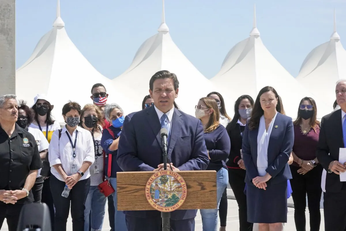Florida Gov. Ron DeSantis, center, surrounded by officials and cruise workers, speaks during a news conference to announce a lawsuit against the federal government, at Port Miami in Miami, Fla., on April 8, 2021. (Wilfredo Lee/AP Photo)