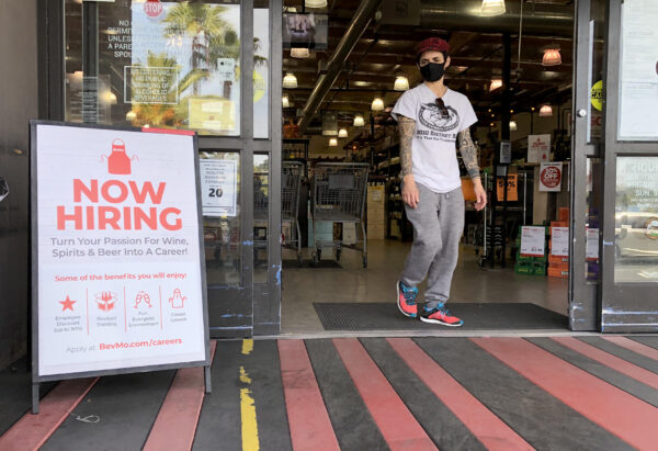 A customer walks by a now hiring sign