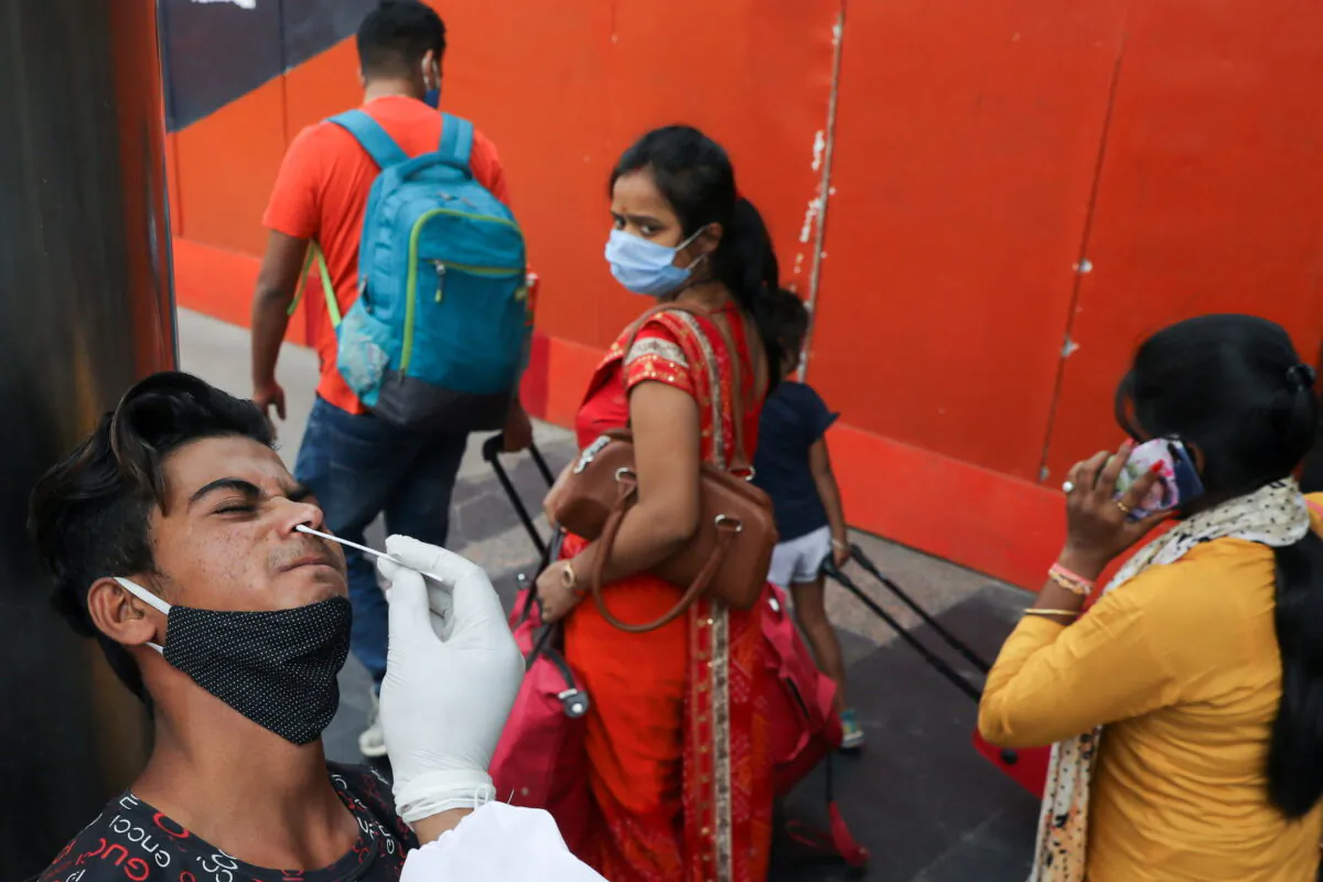 A man reacts as a healthcare worker collects a swab sample, amidst the spread of the coronavirus disease (COVID-19), at a railway station, in New Delhi, India, on April 7, 2021. (Anushree Fadnavis/Reuters)