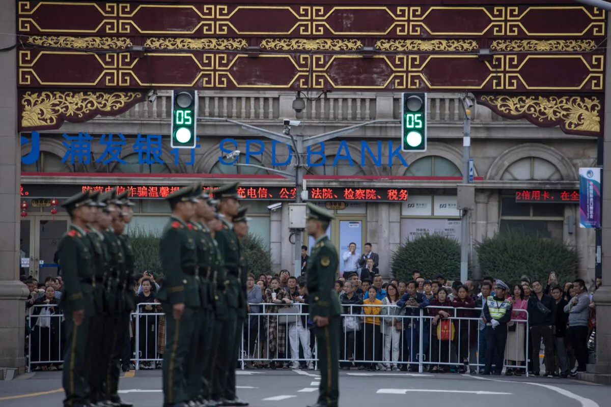 Chinese residents watch as Chinese paramilitary policemen line up in the old city district near the Yu Garden in Shanghai where Chinese President Xi Jinping and French President Emmanuel Macron are expected to have a state dinner in Shanghai on Nov. 5, 2019. (Ng Han Guan/Pool/AFP via Getty Images)