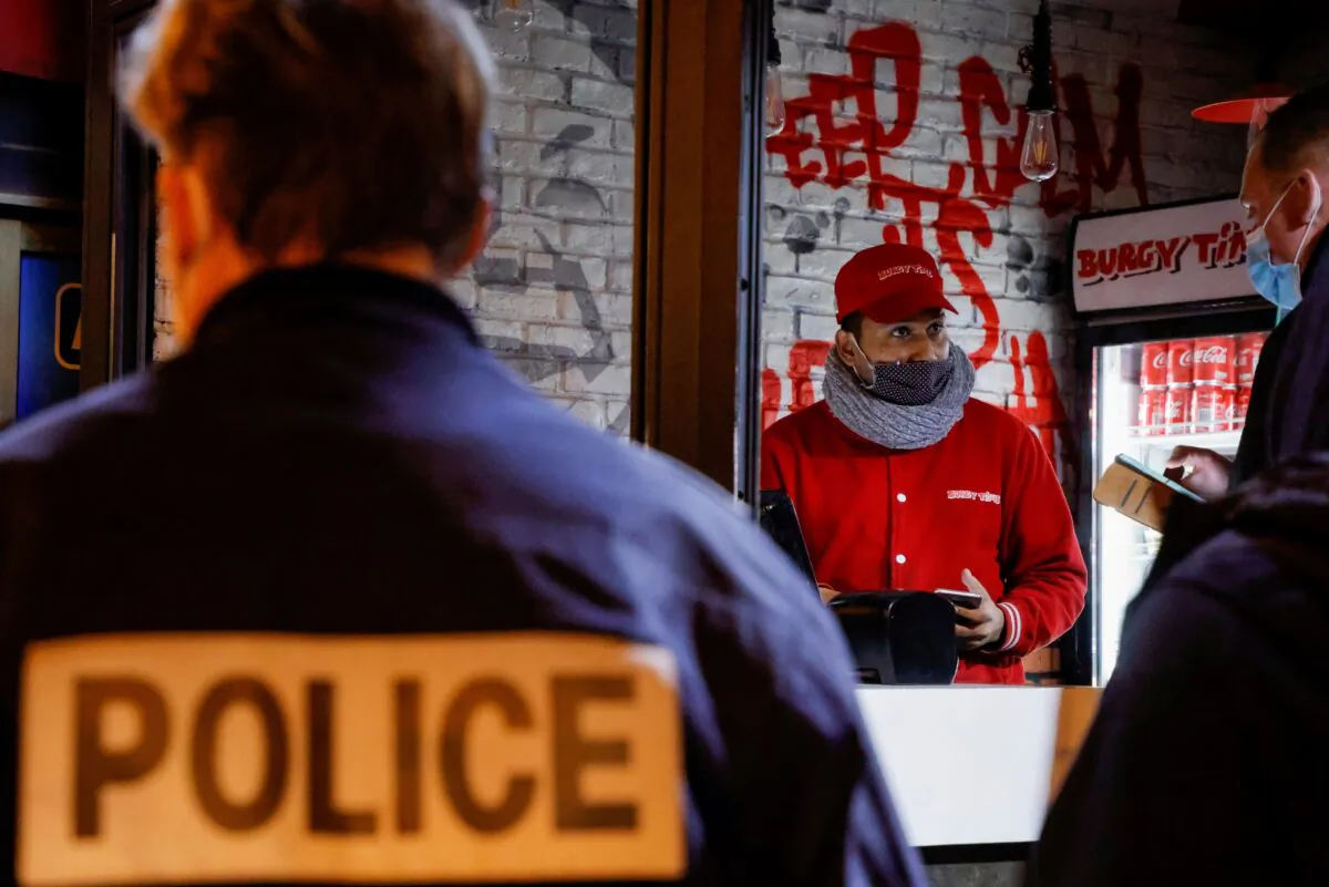 French police officers inspect a restaurant during a nationwide curfew, from 6 p.m to 6 a.m, due to tighter measures against the spread of the CCP virus disease (COVID-19), in Paris on Feb. 5, 2021. (Sarah Meyssonnier/Reuters)