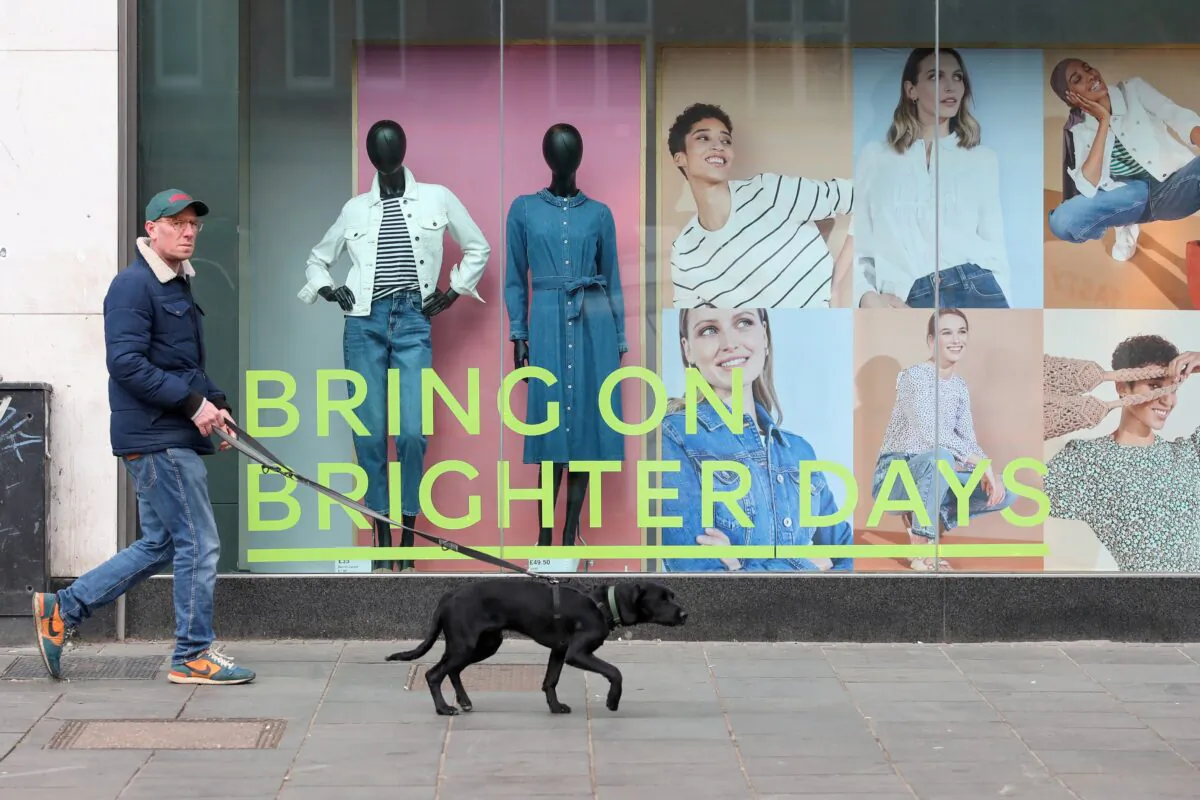 A man walks a dog in front of a closed retail unit ahead of next week's planned reopening, amid the outbreak of the coronavirus disease (COVID-19) in St Albans, Britain, on April 8, 2021. (Peter Cziborra/Reuters)
