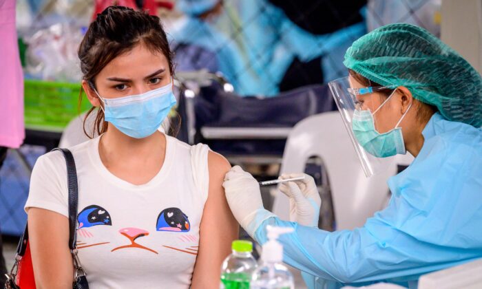 A health worker administers the CoronaVac vaccine, developed by China's Sinovac firm, to a woman from an at-risk group at Saeng Thip sports ground in Bangkok, Thailand, on April 7, 2021. (Mladen Antonov/AFP via Getty Images)