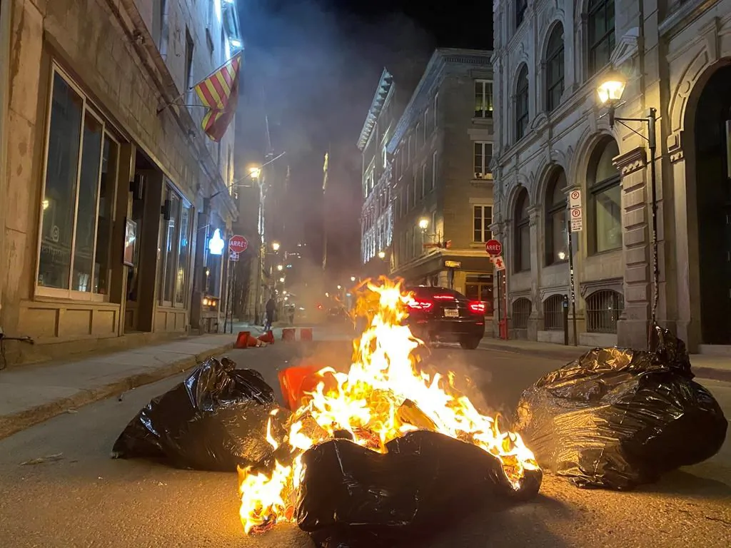 Garbage fires were lit as hundreds of people gathered on Sunday evening in the streets of Old Montreal to protest against the return of the 8 p.m. curfew in the city. (The Canadian Press)