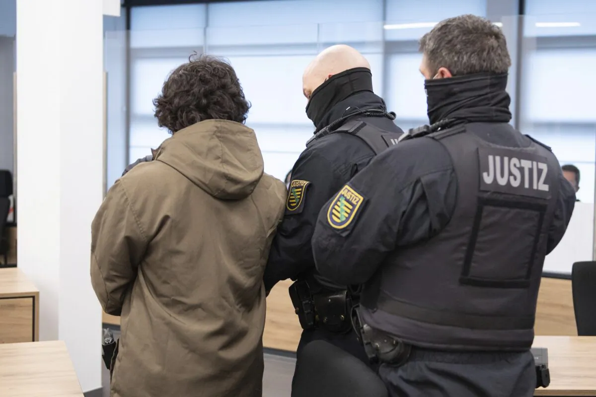 A defendant is led into the hearing room of the Higher Regional Court by court officials before the trial begins in Dresden, Germany, on April 12, 2021. (Sebastian Kahnert/AP via Pool)