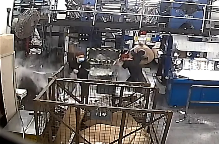 A CCTV screenshot showing intruders dressed in black, one wielding a sledgehammer, damaging printing press equipment  at the print shop of the Hong Kong edition of The Epoch Times on April 12, 2021. (Epoch Times)