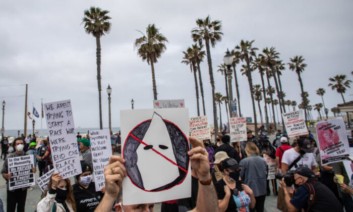 A man holds an anti-KKK sign during a protest against white supremacy in Huntington Beach, Calif., on April 11, 2021. (Apu Gomes/Getty Images)