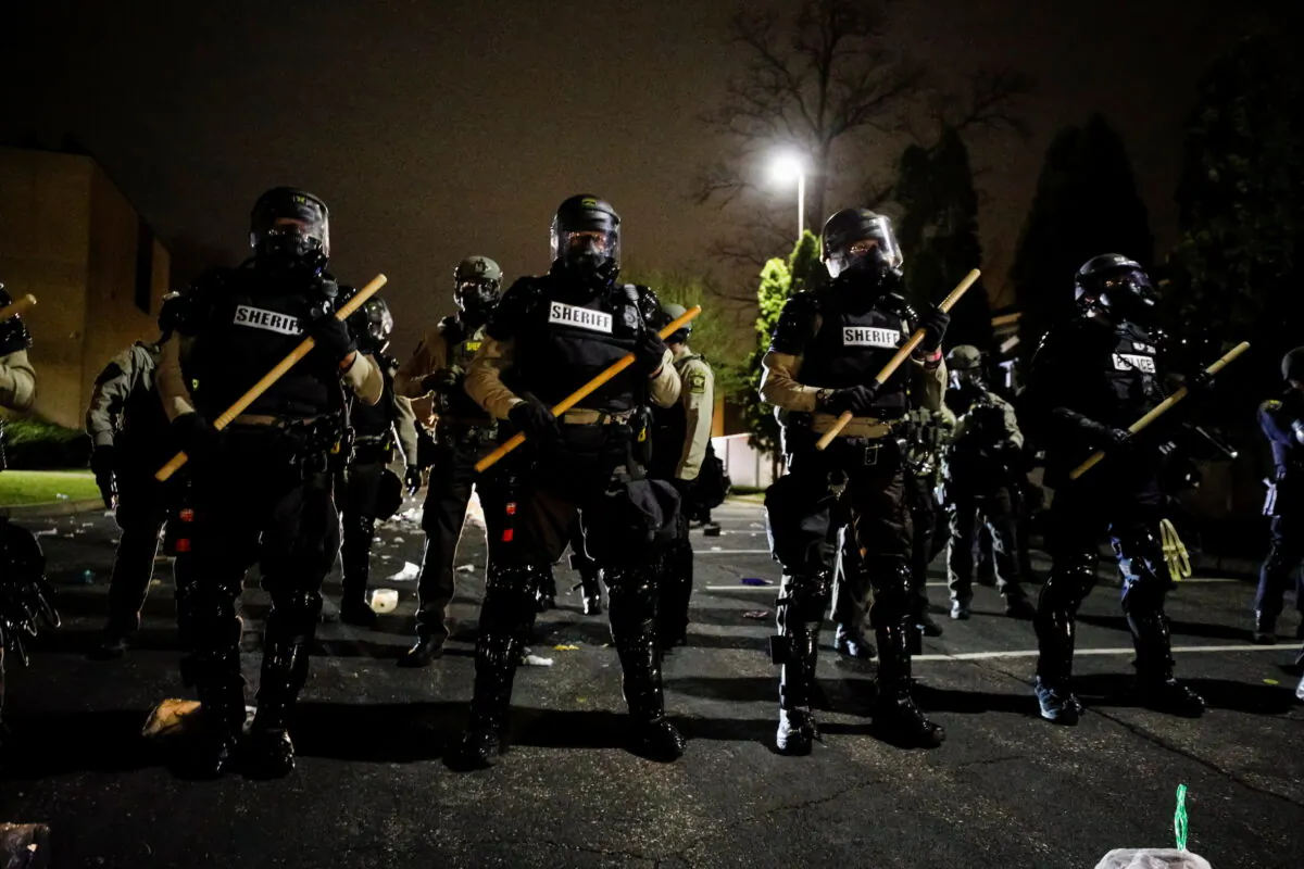 Officers stand guard outside Brooklyn Center Police Department with trash thrown at them by demonstrators at their feet after police allegedly shot and killed a man, who local media report is identified by the victim's mother as Daunte Wright, in Brooklyn Center, Minn., on April 11, 2021. (Nick Pfosi/Reuters)