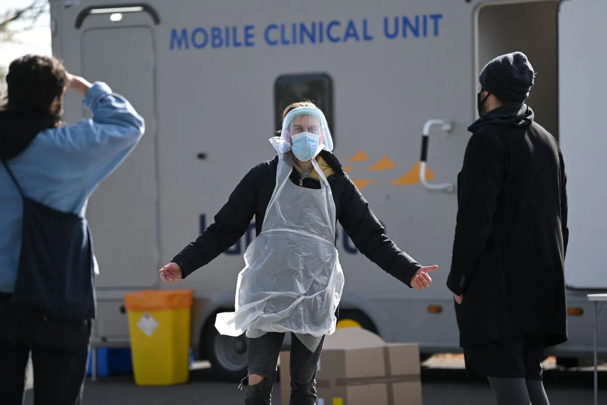 A worker dressed in PPE talks with members of the public arriving to take COVID-19 tests at a mobile novel coronavirus surge testing centre in Brockwell Park in south London, on Apr. 13, 2021. (Daniel Leal-Olivas/AFP via Getty Images)