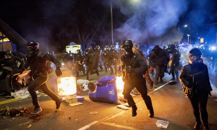 Portland police officers chase demonstrators after a riot was declared during civil unrest over the shooting in Minnesota of Daunte Wright, in Portland, Ore., on April 12, 2021. (Nathan Howard/Getty Images)