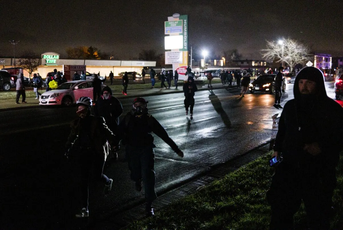 People run from law enforcement officers after trying to tear down fencing and lobbing projectiles at officers, near the Brooklyn Center police headquarters in Brooklyn Center, Minn., on April 13, 2021. (Stephen Maturen/Getty Images)