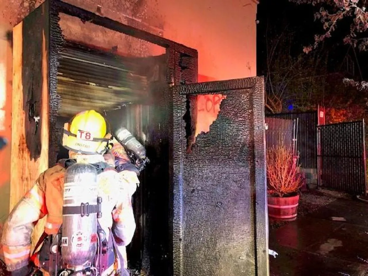 A firefighter helps put out a fire set at the Portland Police Association's headquarters in Portland, Ore., overnight April 14, 2021. (Portland Police Bureau)