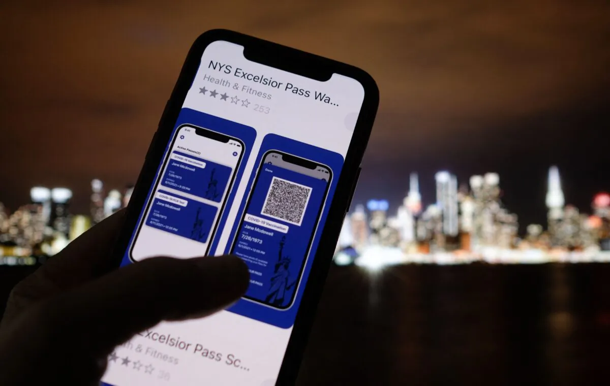 This illustration photo taken in Los Angeles on April 6, 2021 shows a person looking at the app for the New York State Excelsior Pass, which provides digital proof of a COVID-19 vaccination, in front of a screen showing the New York skyline. (Chris Delmas/AFP via Getty Images)