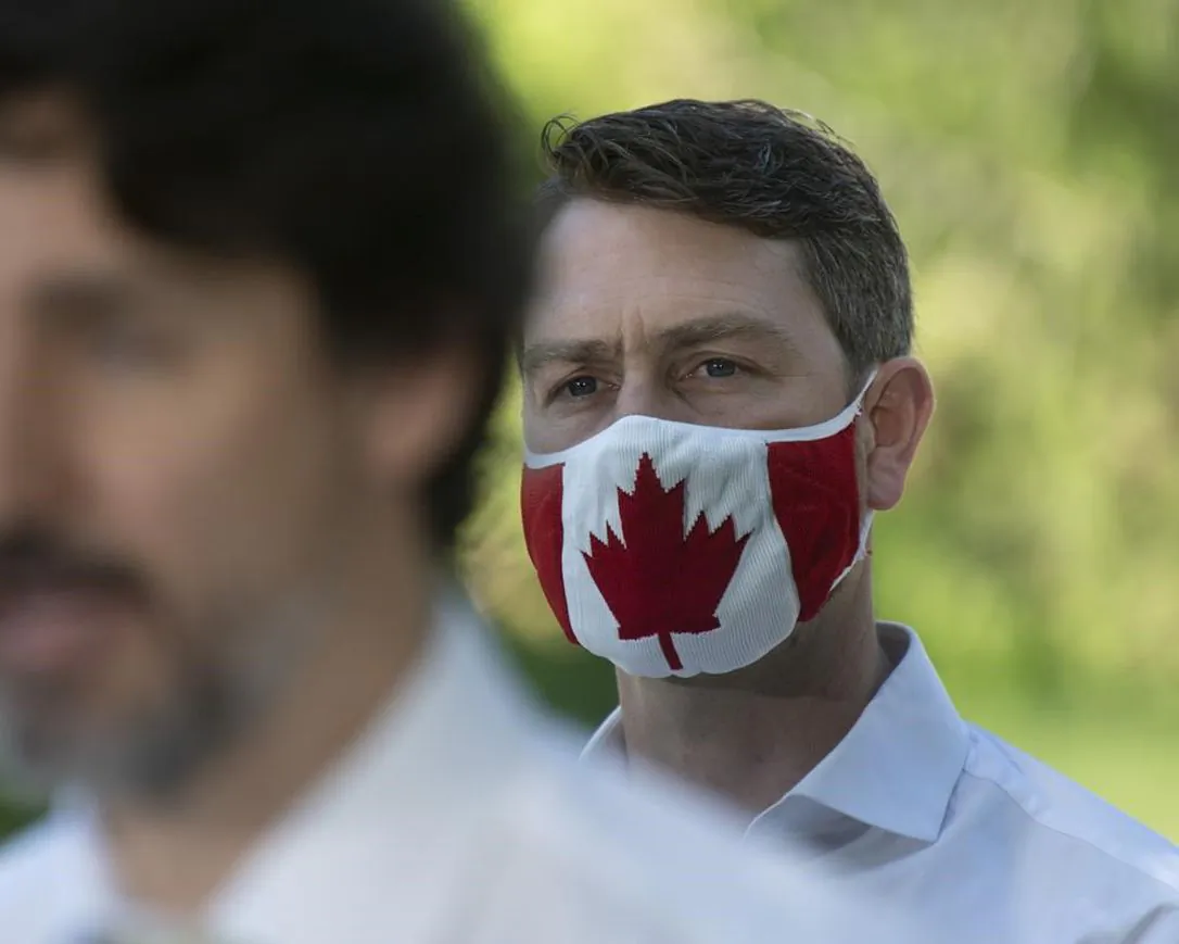 Liberal Member of Parliament William Amos wears a Canadian flag mask as Prime Minister Justin Trudeau speaks during a news conference in Chelsea , Que., on June 19, 2020. (Adrian Wyld / The Canadian Press)