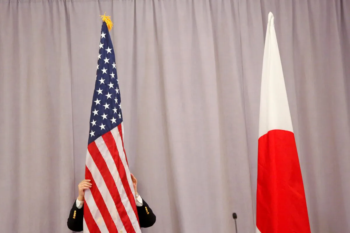 A worker adjusts the U.S. flag before Japanese Prime Minister Shinzo Abe addresses media following a meeting with President-elect Donald Trump in Manhattan, New York City, on Nov. 17, 2016. (Andrew Kelly/Reuters)