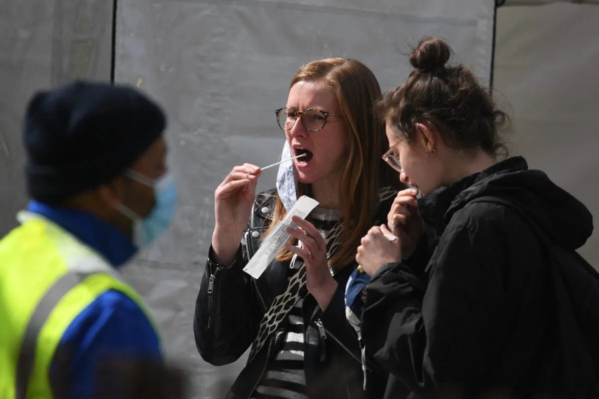 Two women self-administer a COVID-19 test at a mobile novel coronavirus testing centre on Clapham Common in south London, UK, on April 13, 2021. (Daniel Leal-Olivas/AFP via Getty Images)