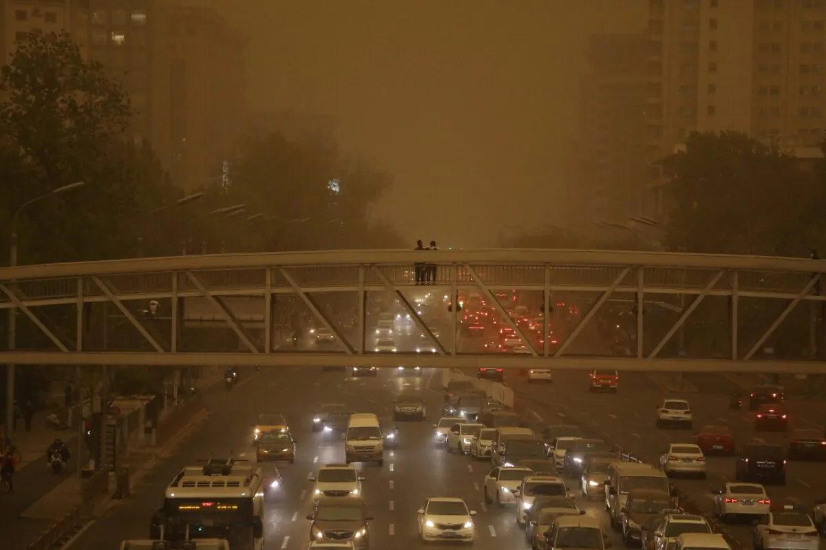 Pedestrians stand on an overpass above car traffic amid a duststorm in Beijing, China, on April 15, 2021. (Tingshu Wang/Reuters)
