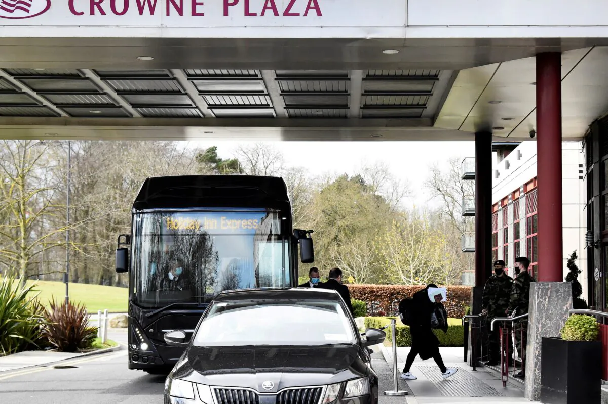 A passenger covers her face after getting off a designated quarantine bus at Crowne Plaza Dublin Airport Hotel, as Ireland introduces hotel quarantine programme for 'high-risk' countries' travellers, in Dublin, Ireland, on March 26, 2021. (Clodagh Kilcoyne/Reuters)