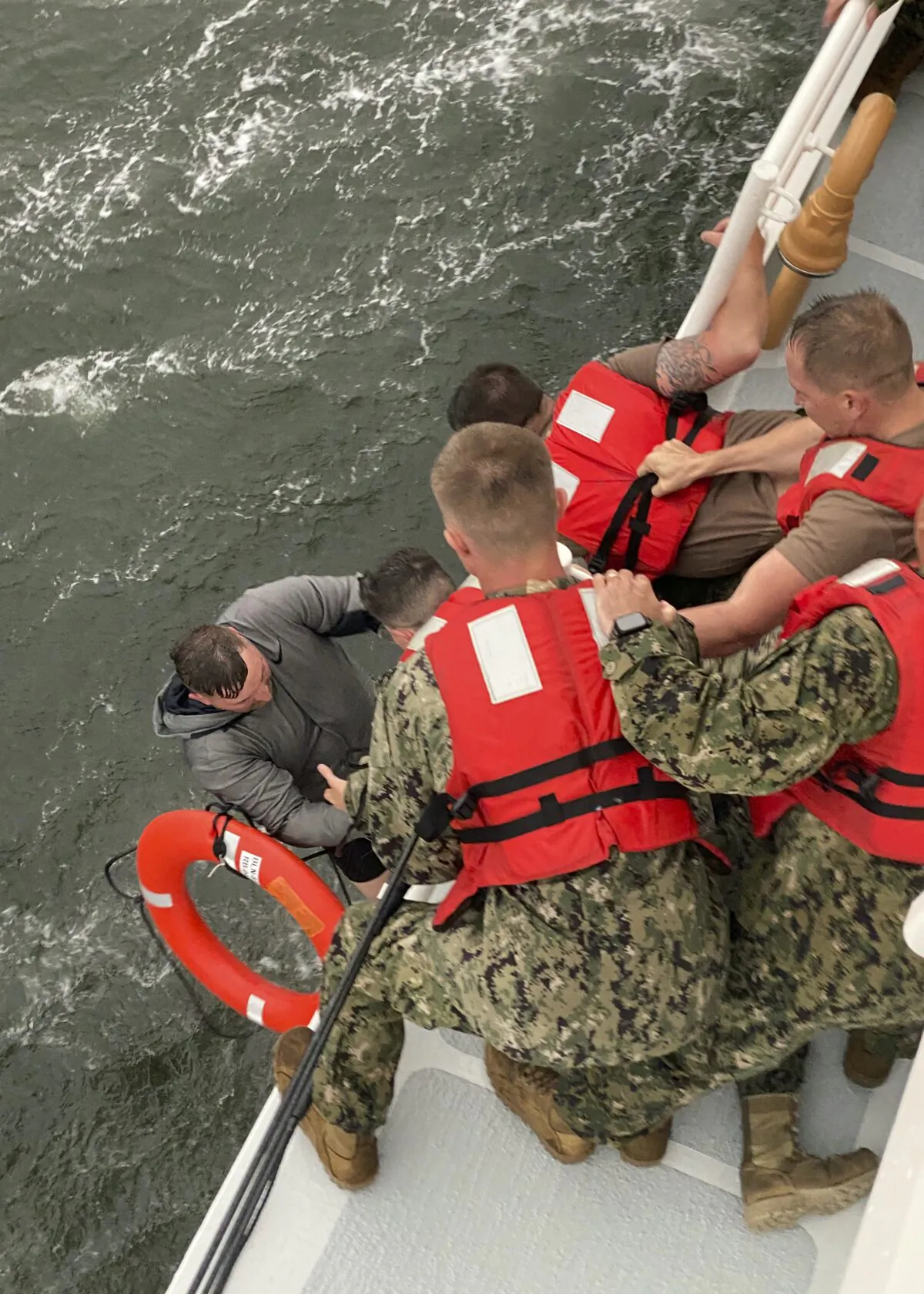 Crew members of the Coast Guard Cutter Glenn Harris pull a person from the water  after a 175-foot commercial lift boat capsized 8 miles south of Grand Isle, La., on April 13, 2021. (U.S. Coast Guard via AP)