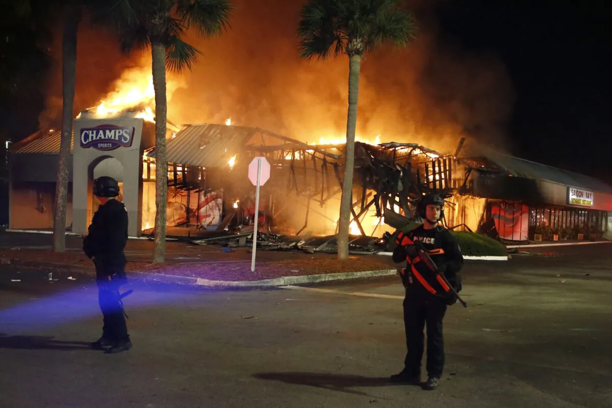 Police SWAT officers guard firefighters as they respond to the Champs Sports store, in Tampa, Fla., on May 31, 2020. (Luis Santana/Tampa Bay Times via AP)