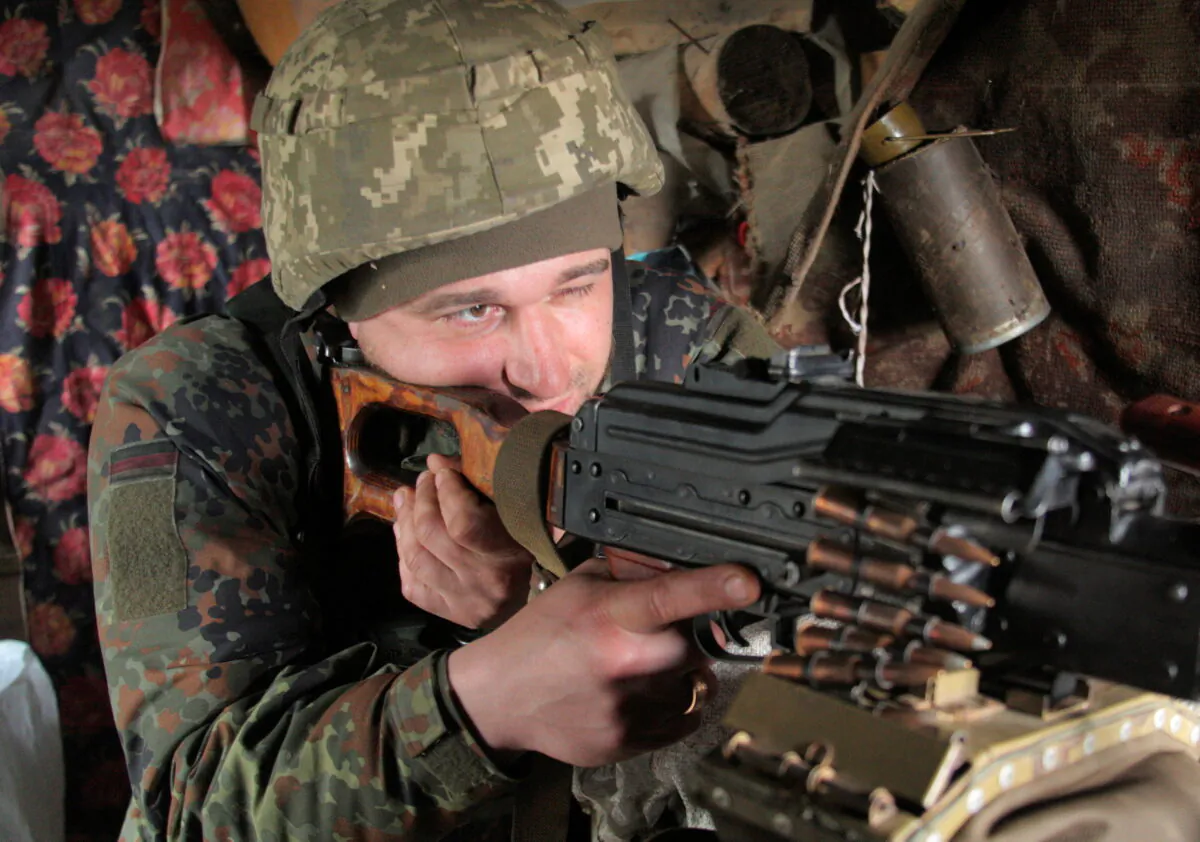 A service member of the Ukrainian armed forces points a weapon at fighting positions on the line of separation near the rebel-controlled city of Donetsk, Ukraine, on Apr. 16, 2021. (Serhiy Takhmazov/ Reuters)