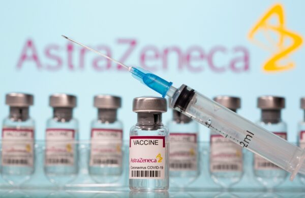 FILE PHOTO: Vials labelled "AstraZeneca COVID-19 Coronavirus Vaccine" and a syringe are seen in front of a displayed AstraZeneca logo