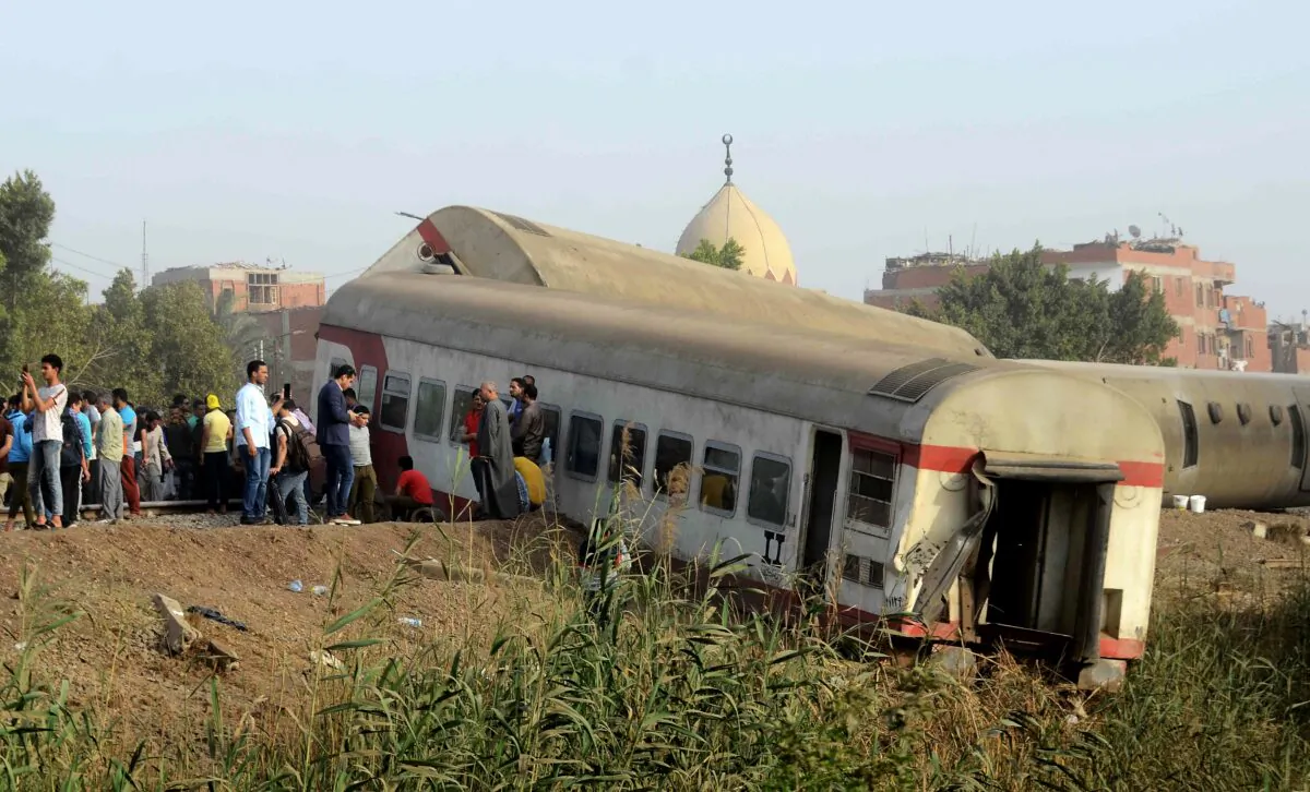 People gather at the site where a passenger train derailed injuring at least 98 people, near Banha, Qalyubia province, Egypt, on April 18, 2021. (Tarek Wagih/AP Photo)