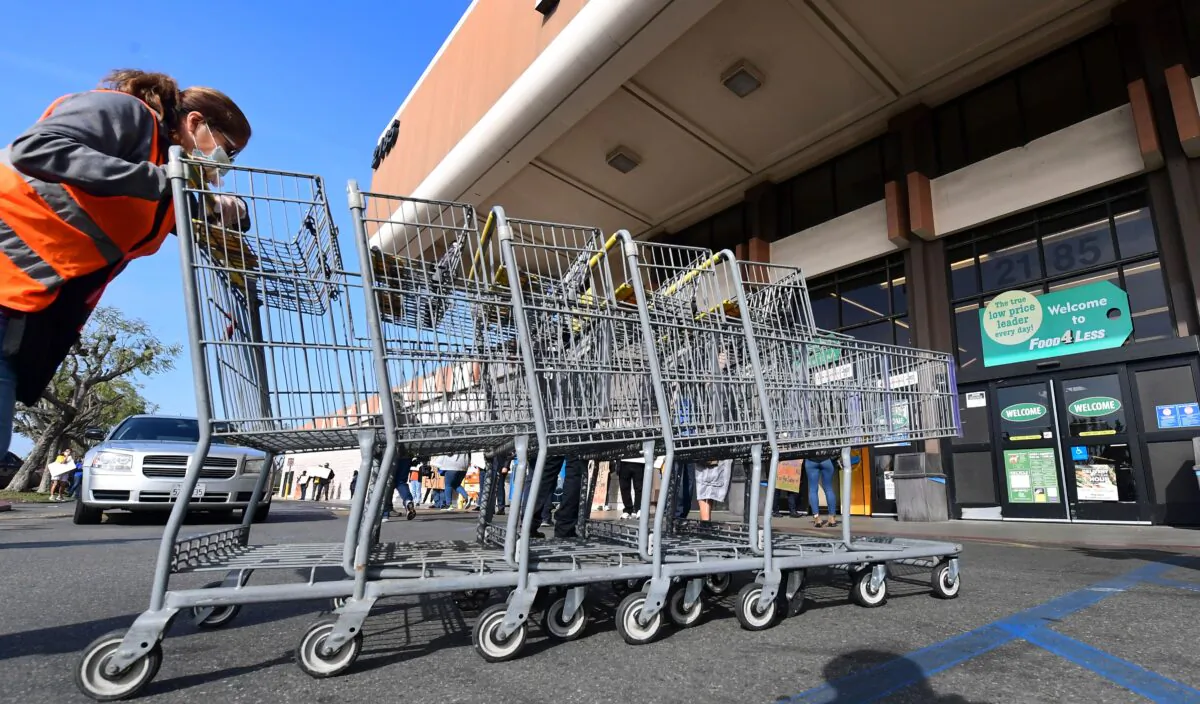A Food 4 Less employee pushes carts past supermarket workers gathered to protest in front of the supermarket in Long Beach, Calif. on Feb. 3, 2021, after a decision by owner Kroger to close two supermarkets rather than pay workers an additional $4 in "hazard pay" for their continued work during the COVID-19 pandemic. (Frederic J. Brown/AFP via Getty Images)