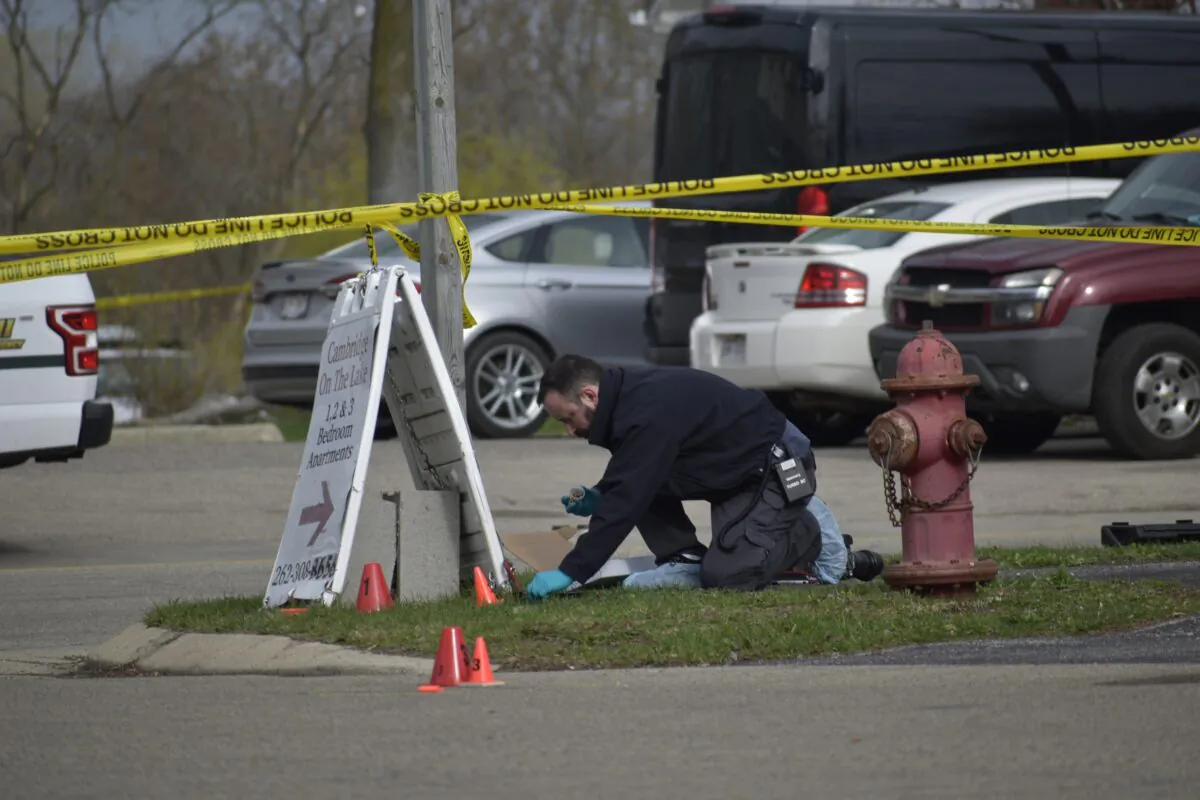 An investigator looks for evidence outside the Somers House Tavern, after a fatal shooting, in Somers, Wis., just outside of Kenosha, on April 18, 2021. (Deneen Smith/The Kenosha News via AP)