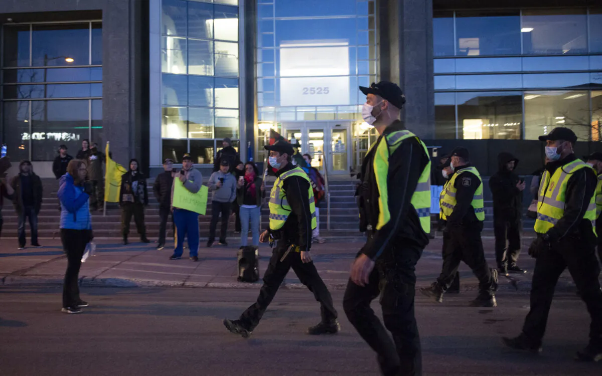 Police officers walk toward anti-curfew demonstrators in front of Quebec Deputy premier and Public Security Minister Genevieve Guilbault's office in Quebec City on April 13, 2021. (Jacques Boissinot/The Canadian Press)
