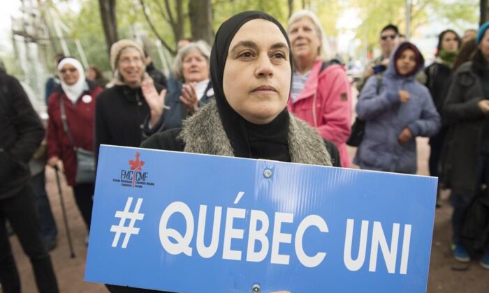 People hold up signs during a demonstration against Bill 21 in Montreal, Sunday, October 6, 2019. The controversial Quebec secularism law bans some public-sector employees from wearing religious symbols in the workplace. (THE CANADIAN PRESS/Graham Hughes)