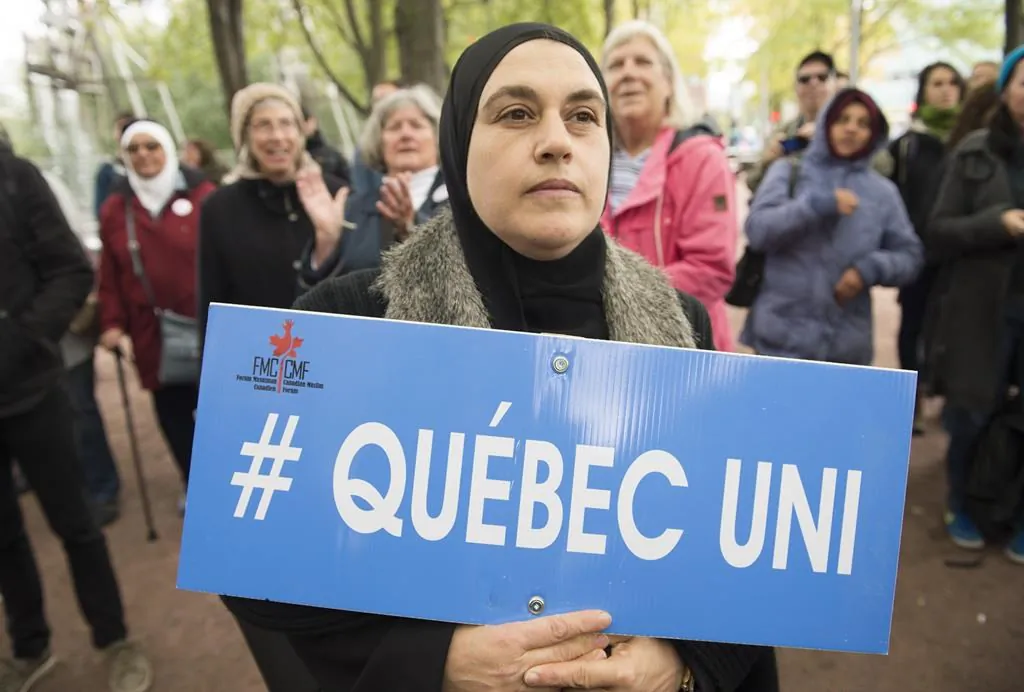 People hold up signs during a demonstration against Bill 21 in Montreal, Sunday, October 6, 2019. The controversial Quebec secularism law bans some public-sector employees from wearing religious symbols in the workplace. (THE CANADIAN PRESS/Graham Hughes)