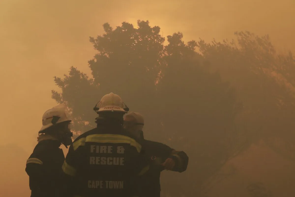 Firefighters keep an eye on a raging fire on the slopes of Table Mountain, in Cape Town  South Africa, Monday, April 19, 2021. Residents in the Vredehoek suburb have been evacuated as a precautionary measure as high winds fanned the fire for a second day. (AP Photo/Nardus Engelbrecht)
