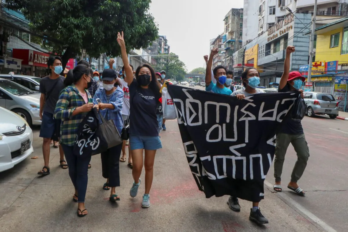 Anti-coup protesters shout slogans with a banner reading ''Carry on revolution! We do not accept as the military slave,'' in Kamayut township of Yangon, Burma, on April 19, 2021. (AP Photo)