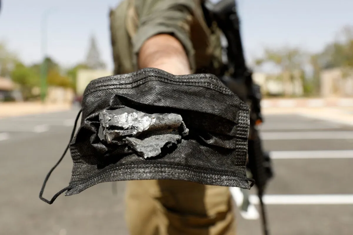 An Israeli soldier holds a piece of debris with a mask after a missile launched from Syria landed in Ashalim settlement, near the Dimona nuclear power plant in Israel's southern Negev desert, on April 22, 2021. (Ahmad Gharabli/AFP via Getty Images)