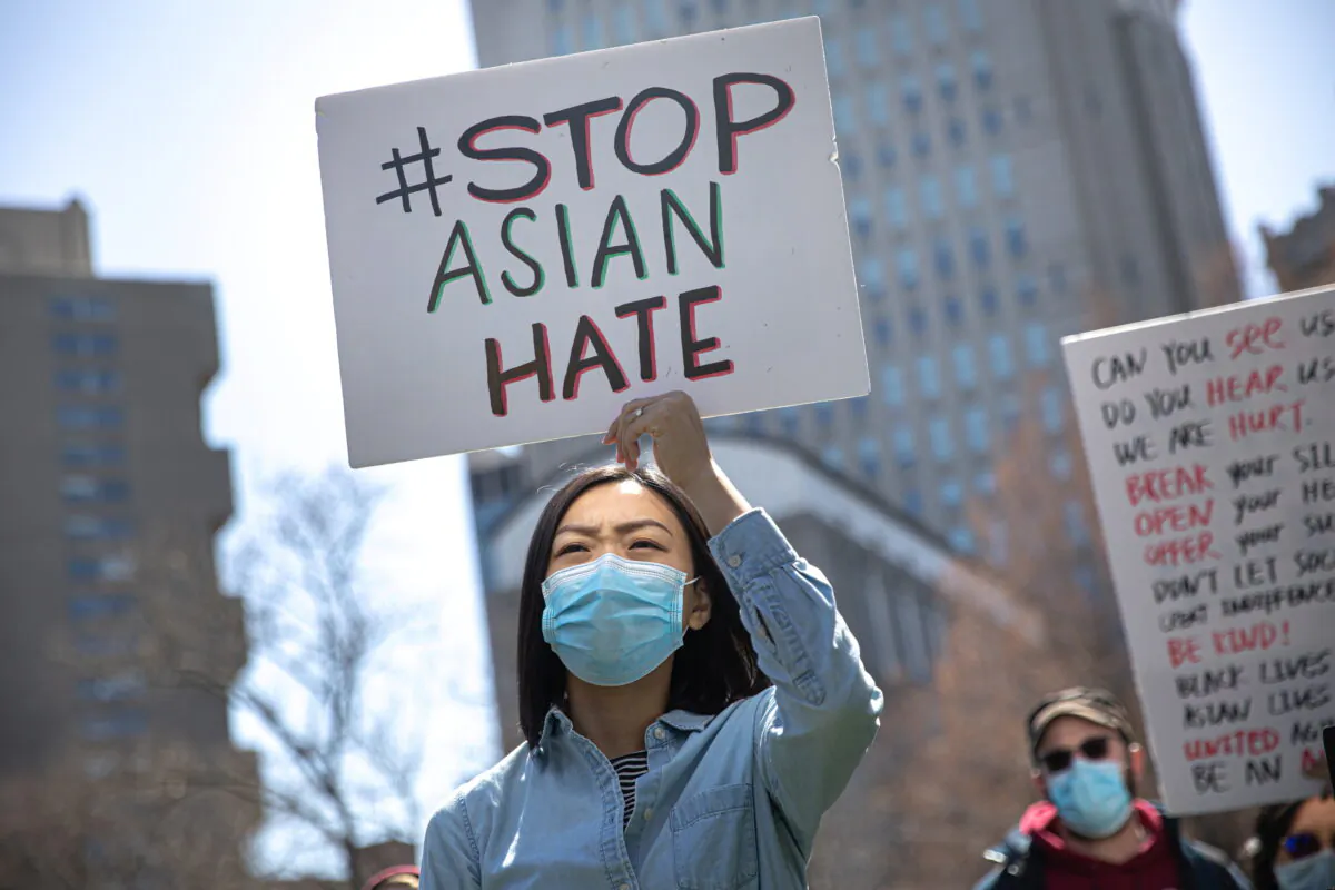 A woman holds a placard as she participates in a Stop Asian Hate rally at Columbus Park in New York City, N.Y., on April 3, 2021. (Reuters/Jeenah Moon)