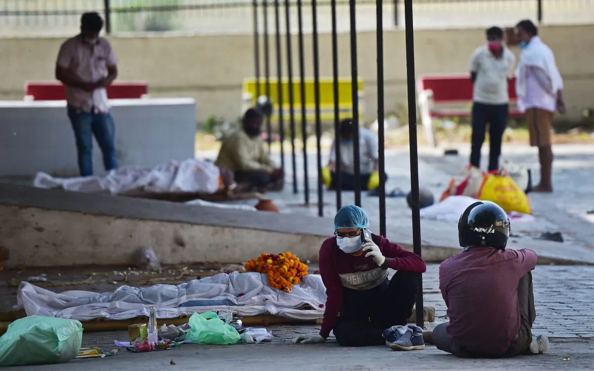 Relatives sit next to the dead bodies of COVID-19 victims at a municipal electric crematorium in Allahabad, India, on April 22, 2021. (Sanjay Kanojia/AFP via Getty Images)