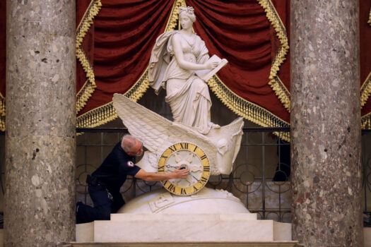 An employee from the Architect of the Capitol adjusts the hands of the Car of History Clock in Statuary Hall at the U.S. Capitol in Washington, D.C., on Oct. 31, 2019. (Chip Somodevilla/Getty Images)