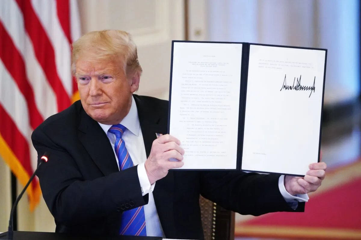Former President Donald Trump holds an executive order he signed at the White House in Washington on June 26, 2020 to establish a 20-person Advisory 1776 Commission under the Department of Education to promote “patriotic education.” The commission was terminated by President Joe Biden on Jan. 20, 2021. (Mandel Ngan/AFP via Getty Images)