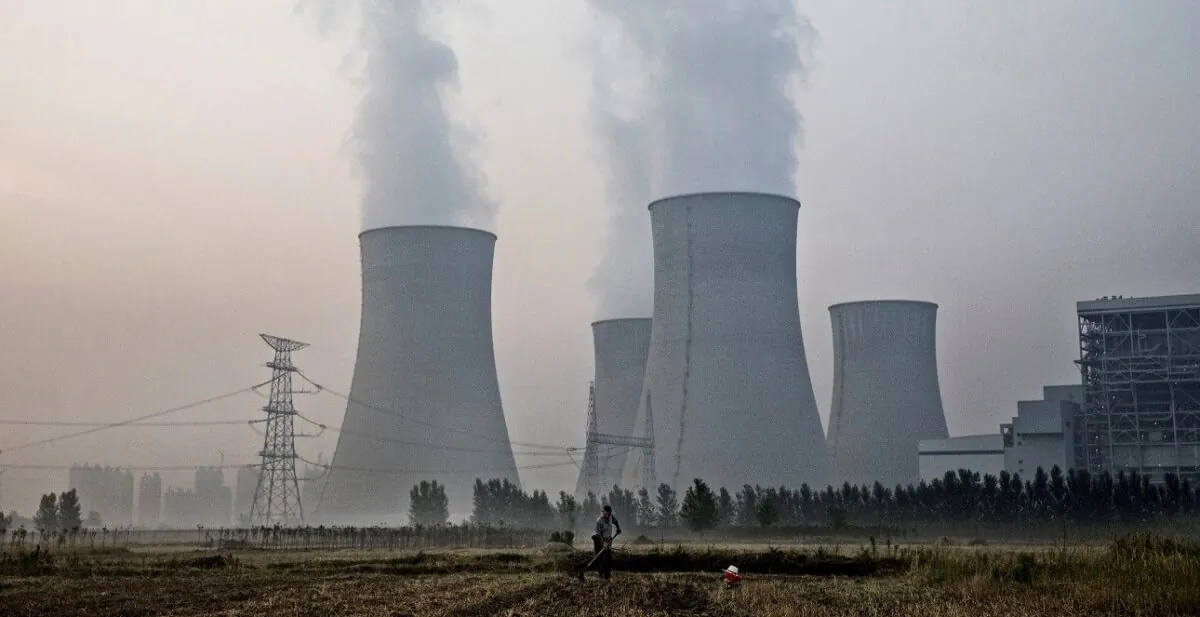 A Chinese farmer works his field next to a state-owned, coal-fired power plant in Huainan, Anhui Province, China, on June 15, 2017. (Kevin Frayer/Getty Images)